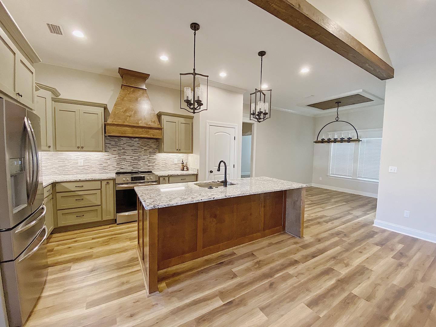 Kitchen with olive cabinets, brown island, and wood beam ceiling.