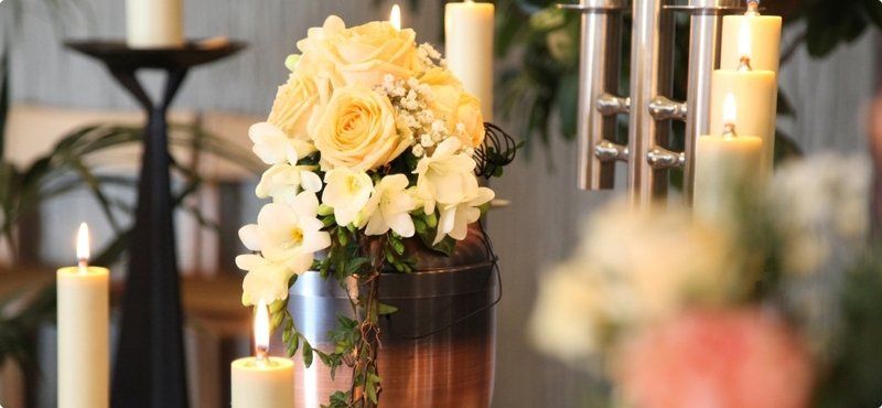 Cremation Services, cremation offered by Nickle Mortuary, brass urn on table with candles and flowers