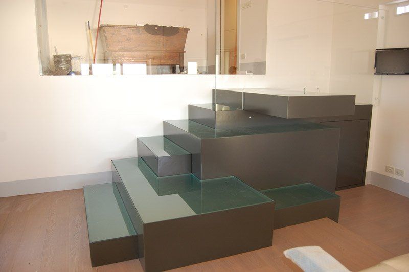 Scala moderna con gradini in vetro e pannelli marrone scuro in una stanza minimalista