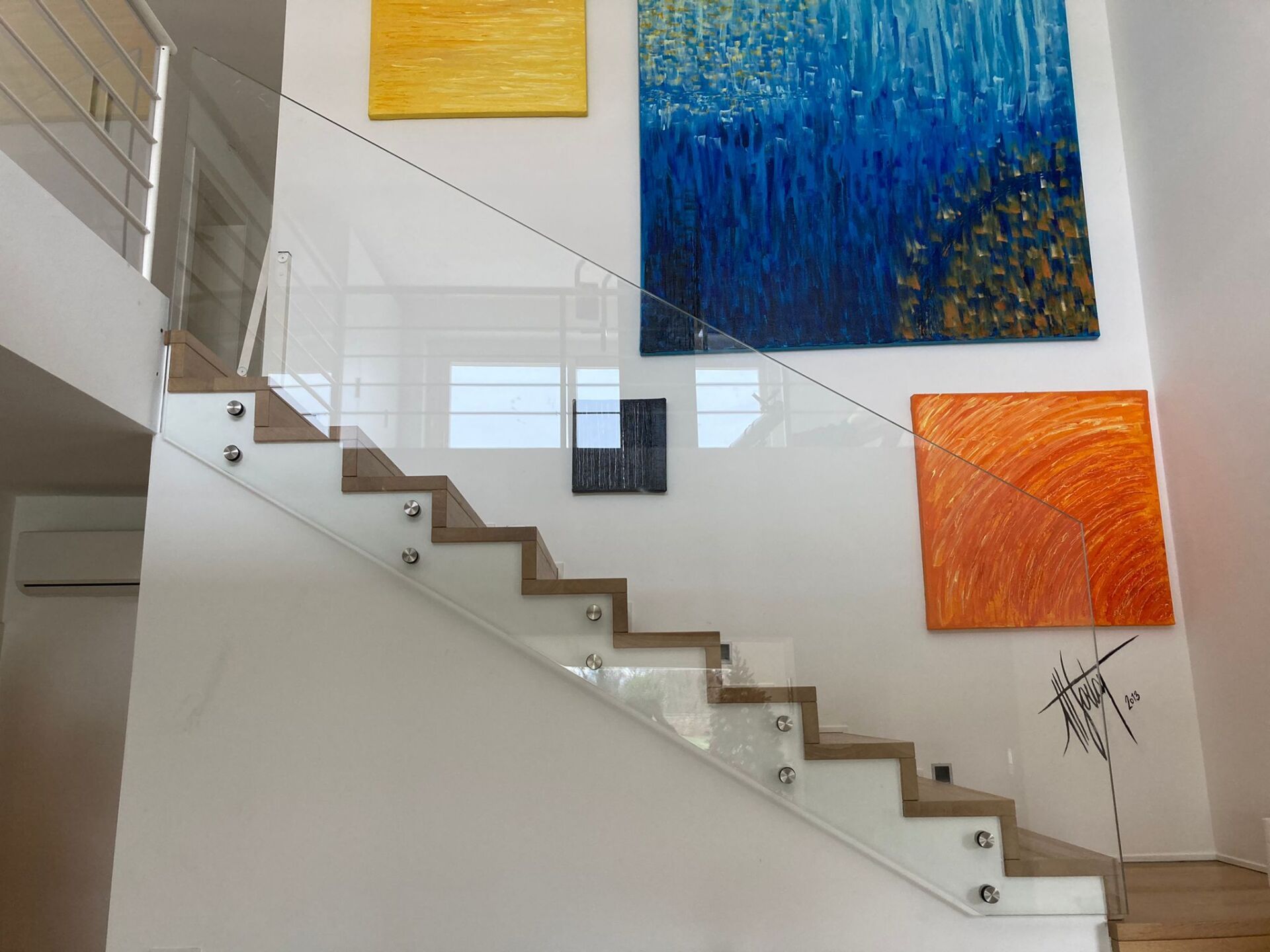 Scala moderna con galleria e dipinti astratti colorati nei toni del giallo, blu, arancione e nero.