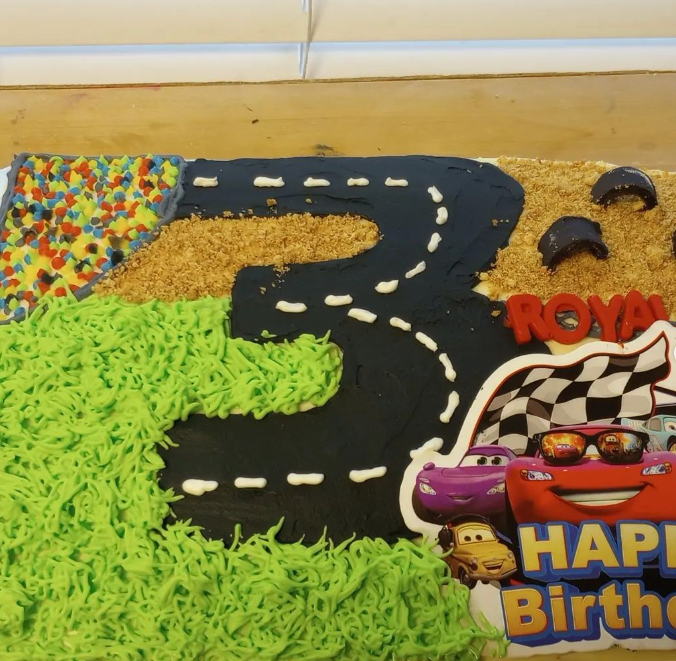 A birthday cake with cars and the number 3 on it