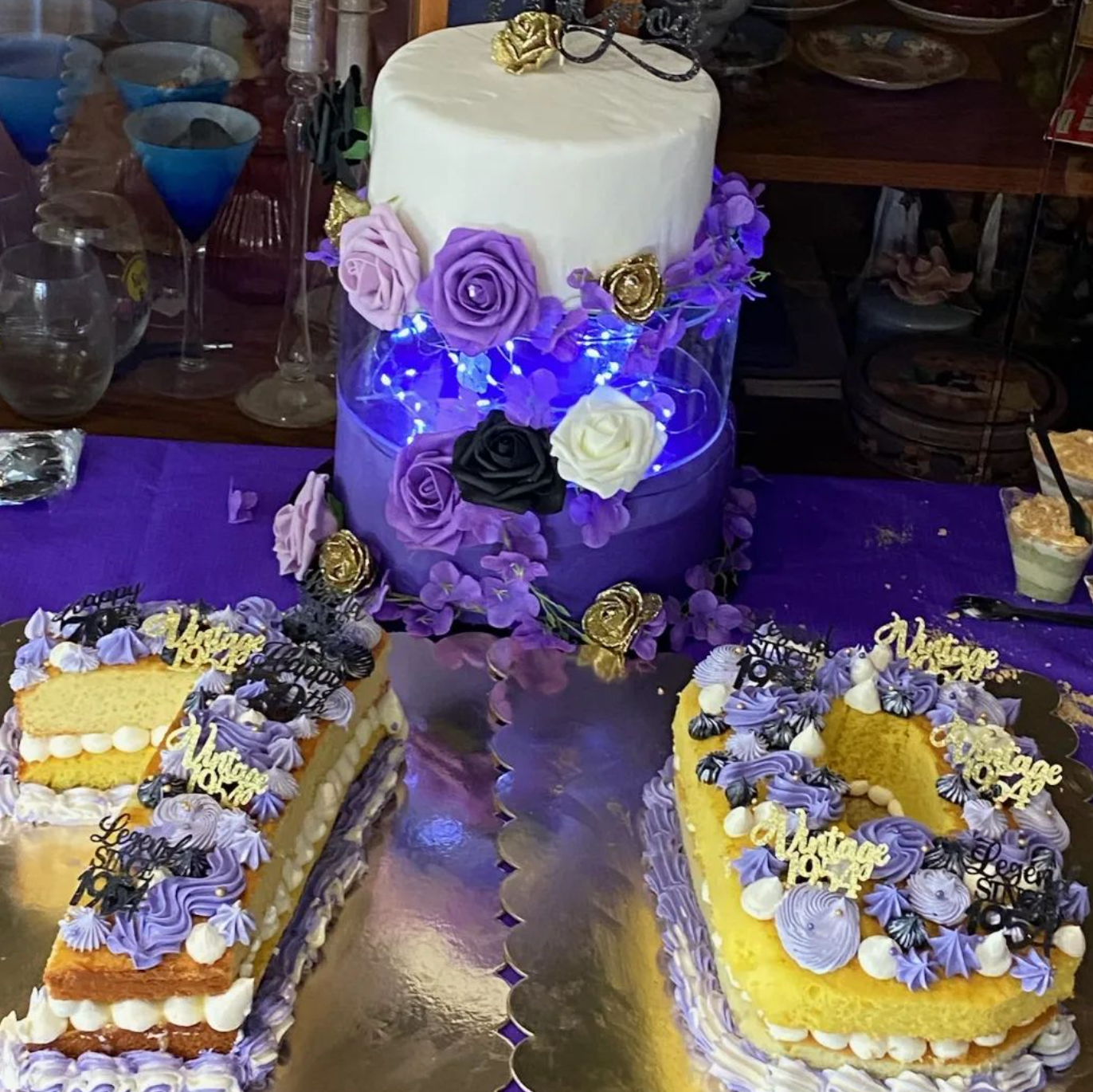 Two cakes with purple frosting and flowers are on a table