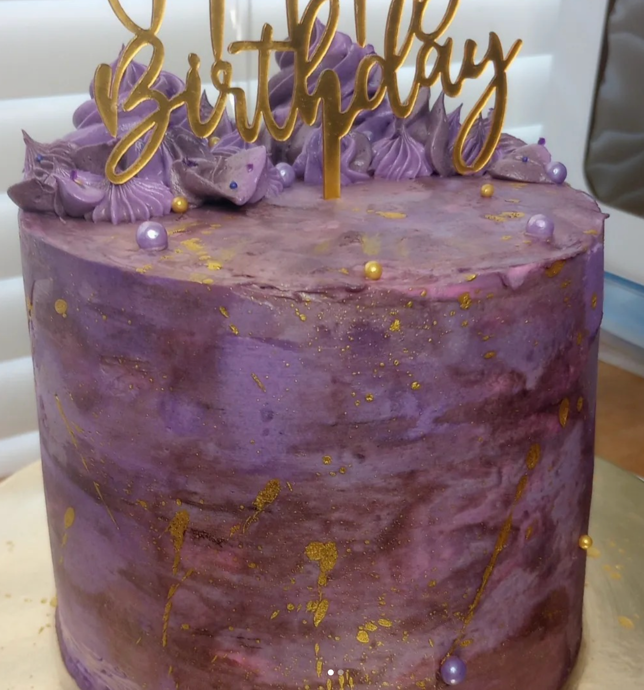 A purple birthday cake with a topper that says birthday