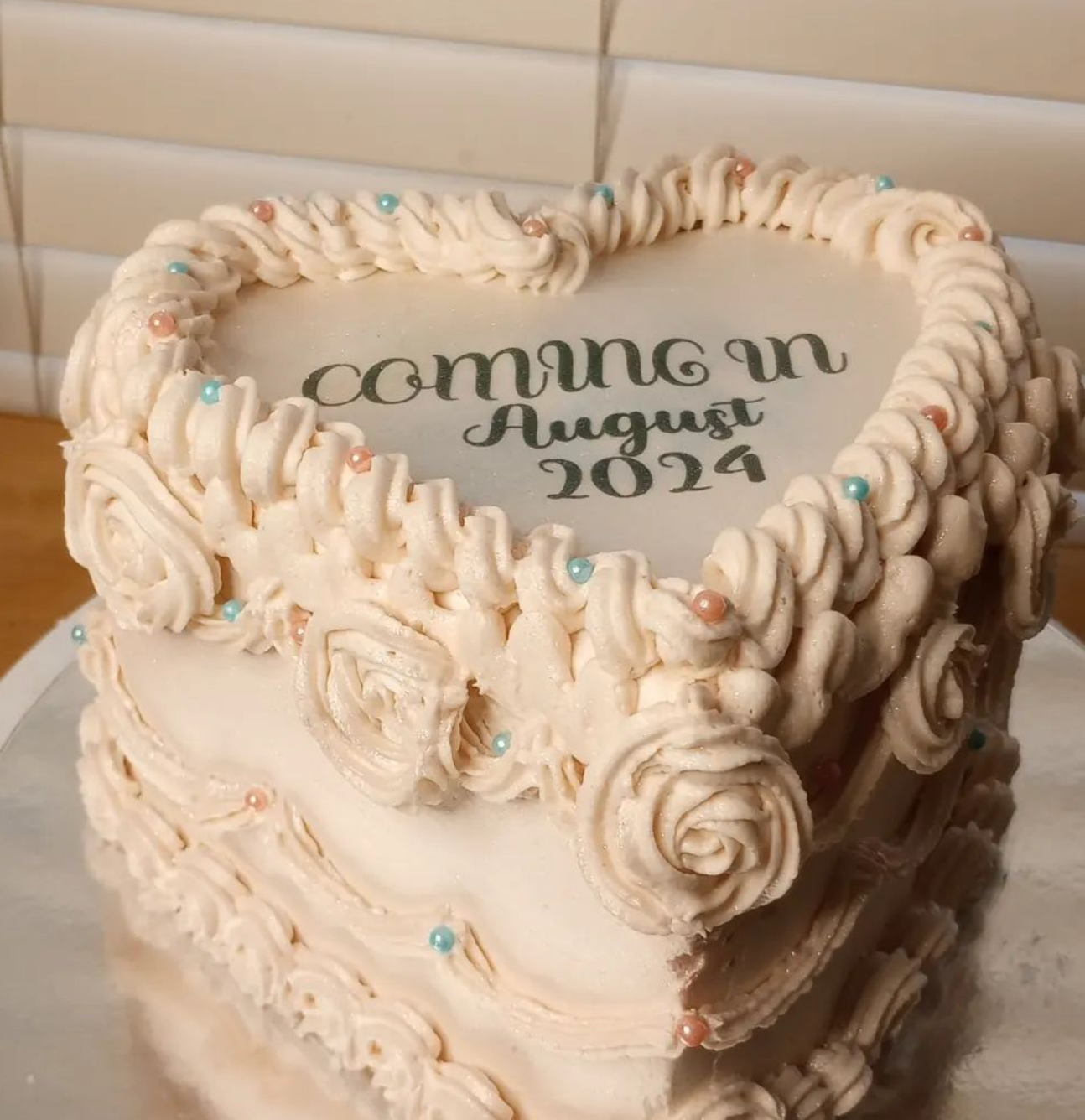 A heart shaped cake that says coming in august 2024