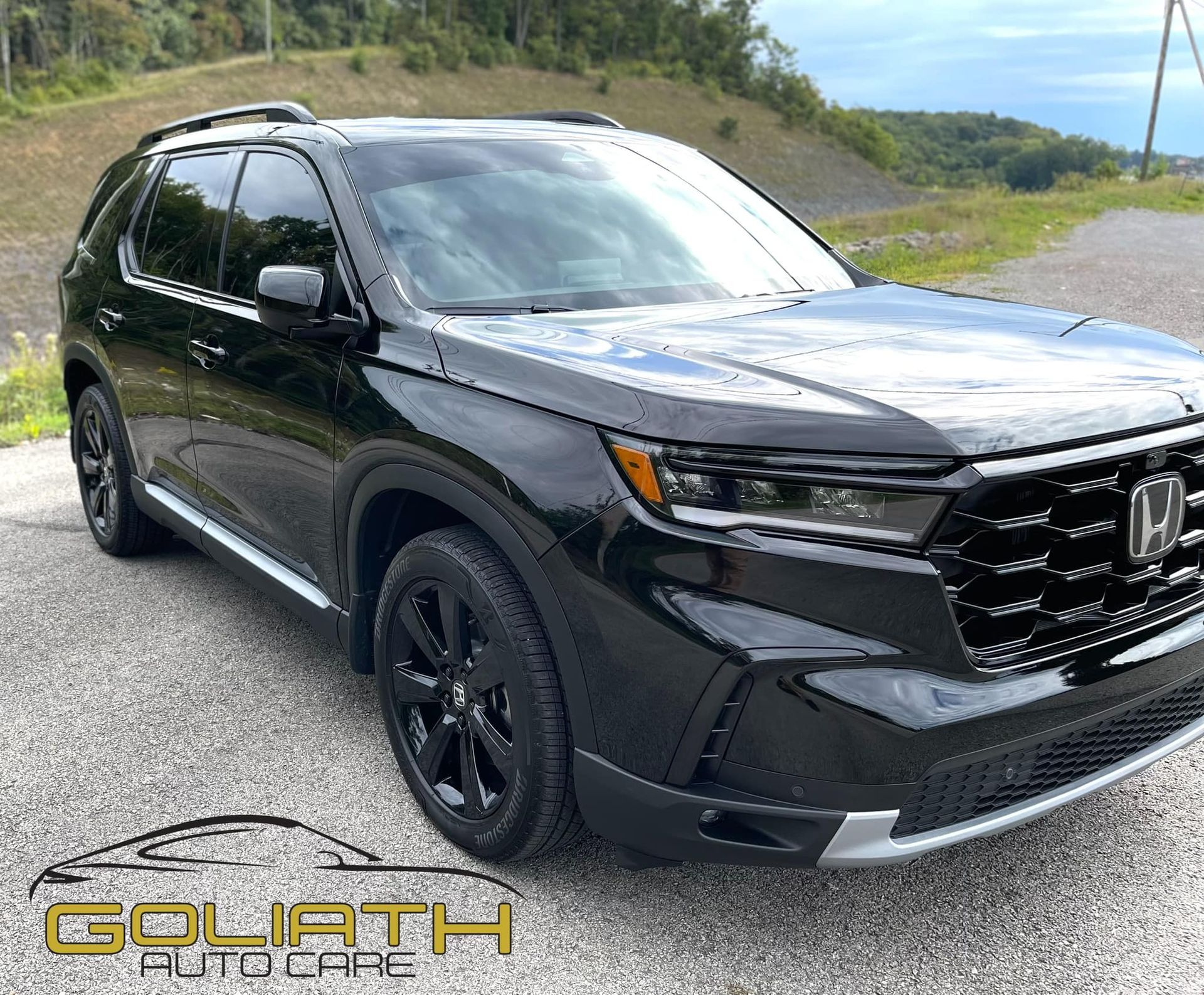 a black honda pilot is parked on the side of the road .