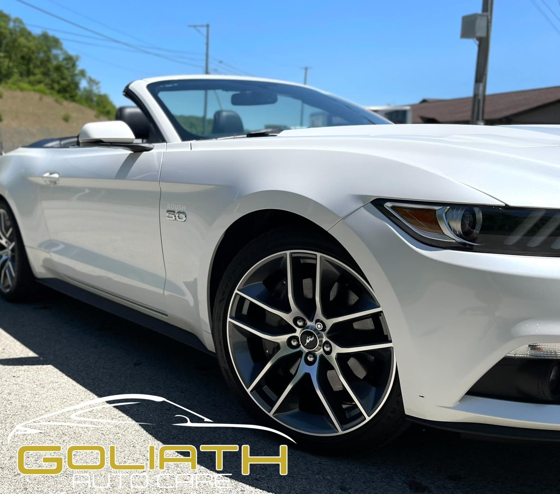 a white convertible mustang is parked on the side of the road