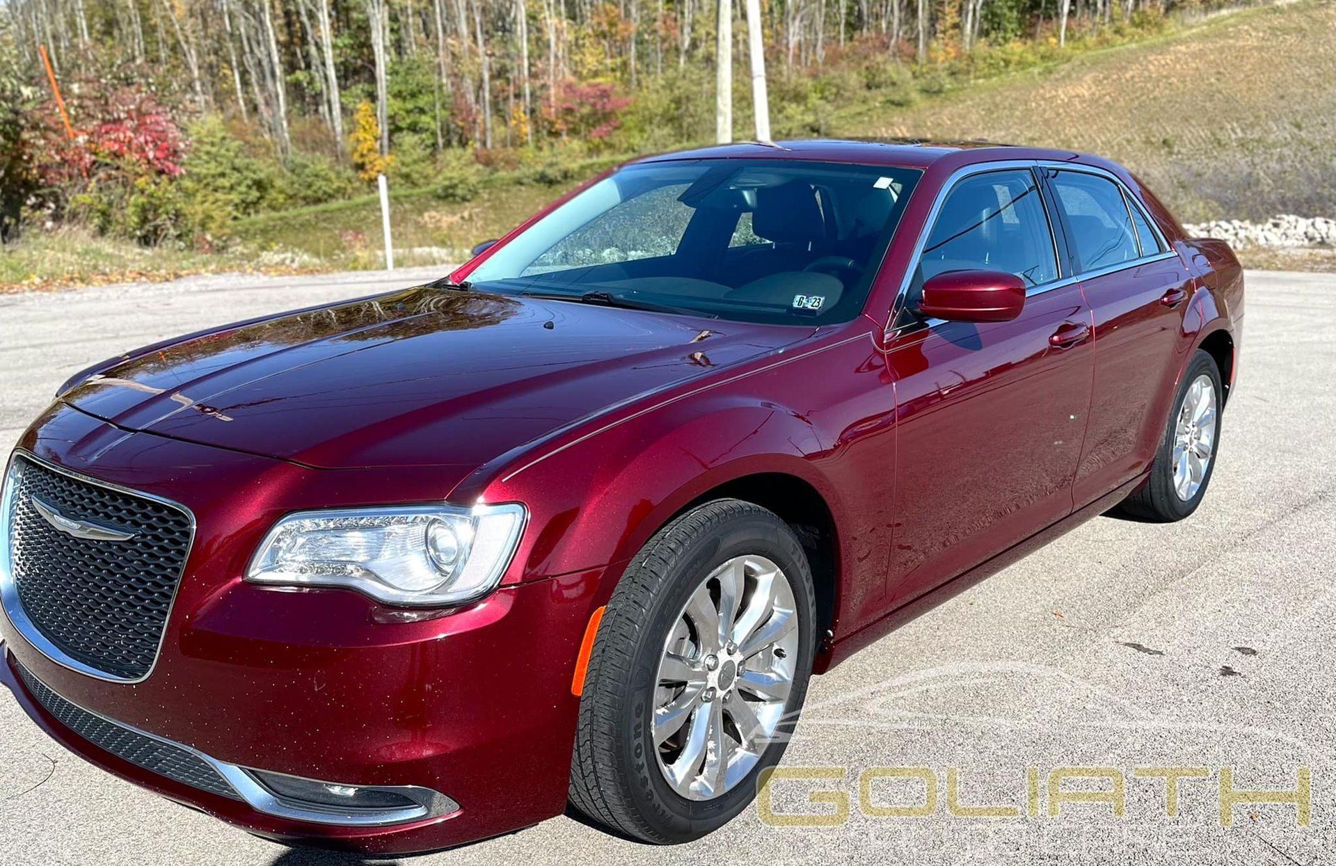 a red chrysler 300 is parked in a parking lot .