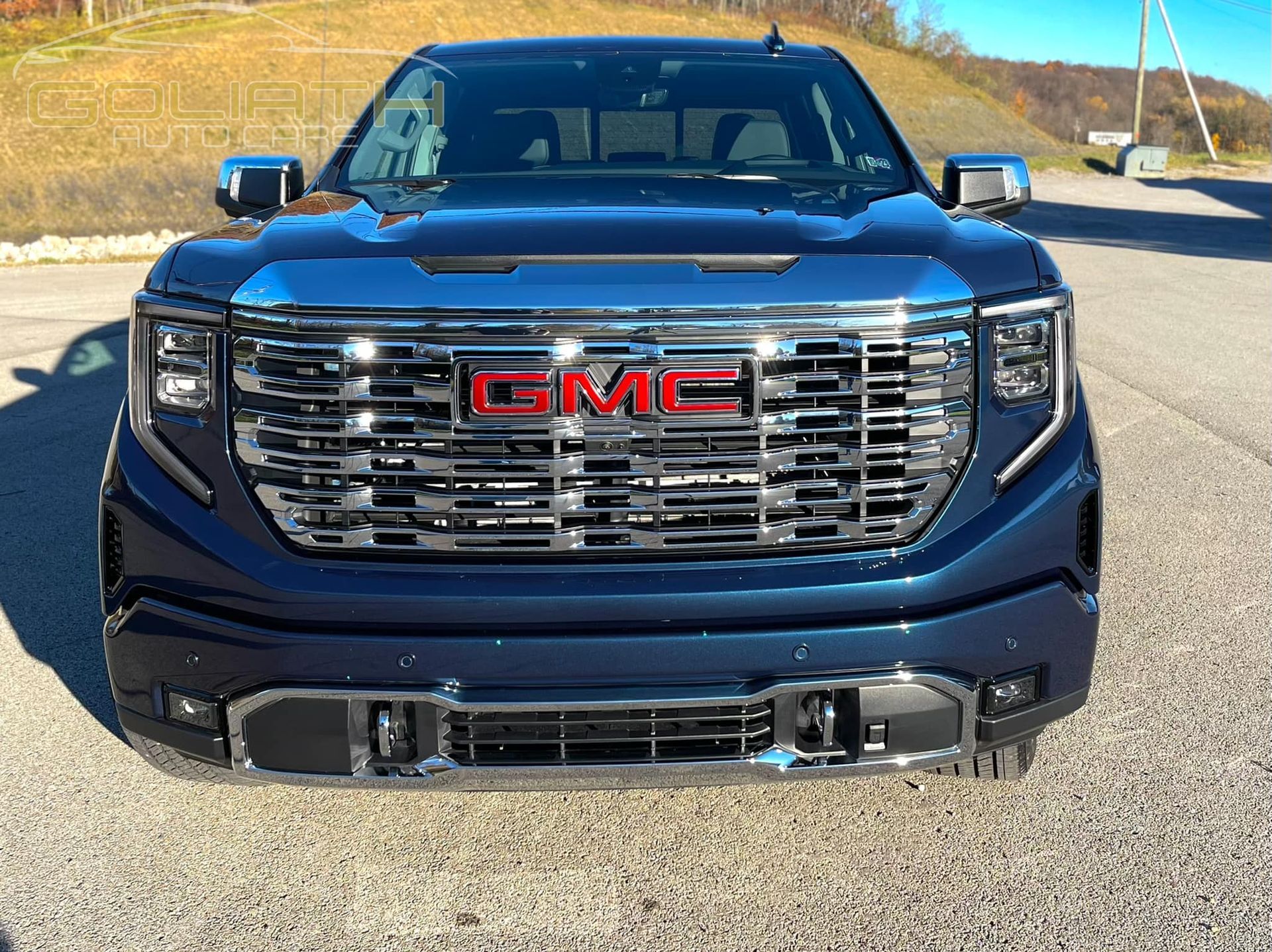 a blue gmc truck is parked on the side of the road .