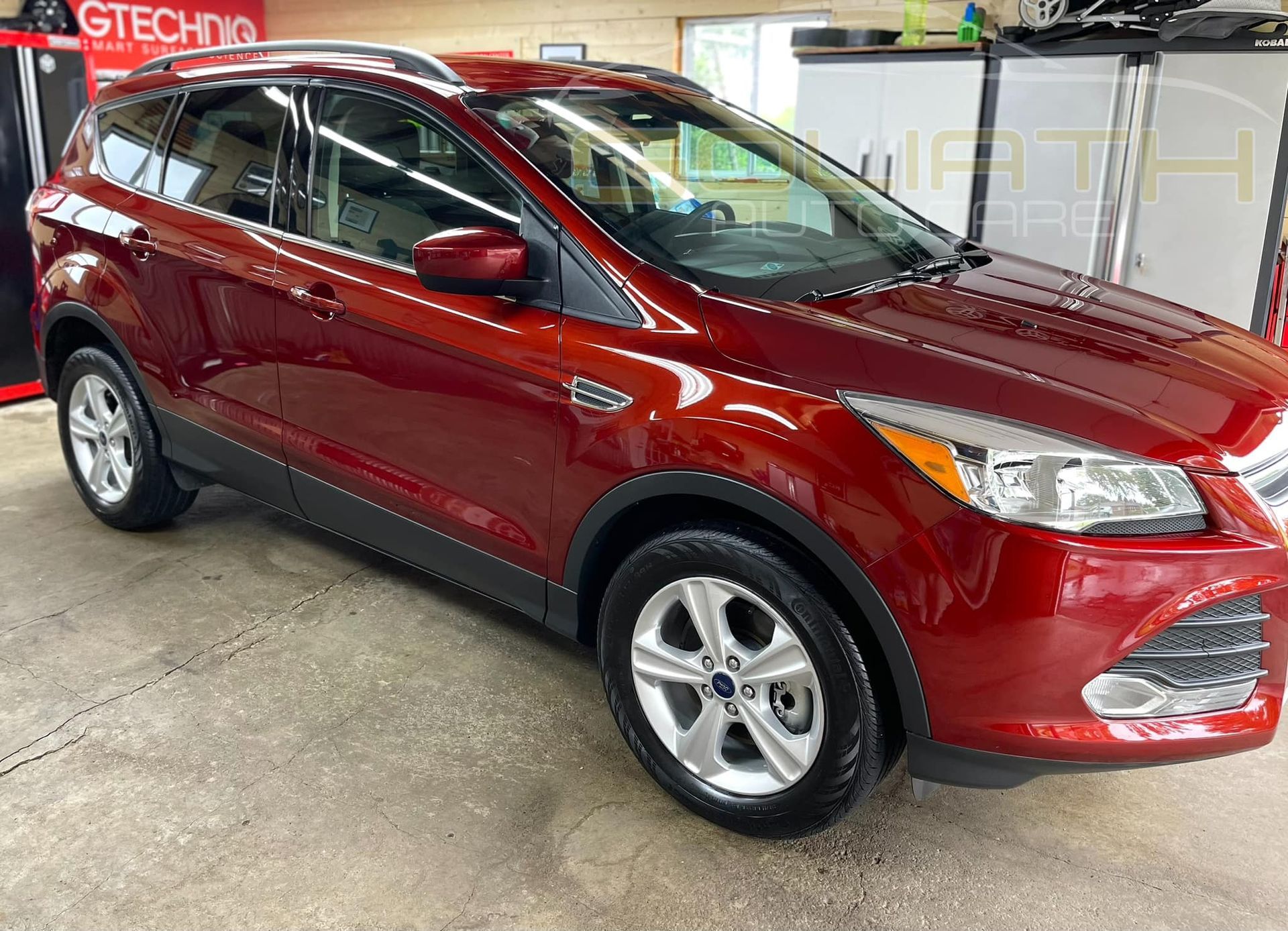 a red ford escape is parked in a garage .