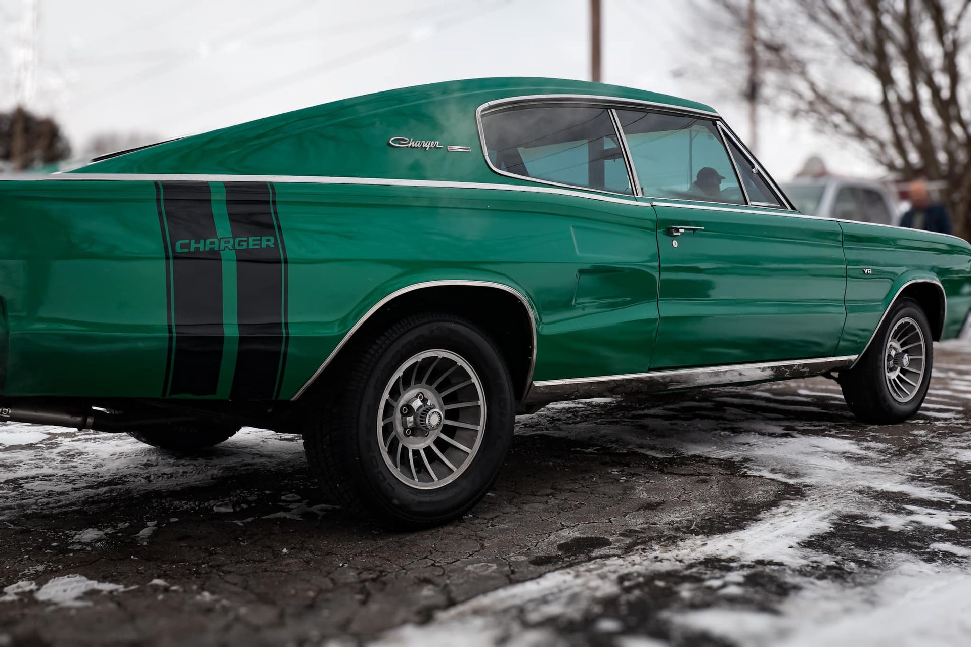 a green muscle car is parked in the snow .