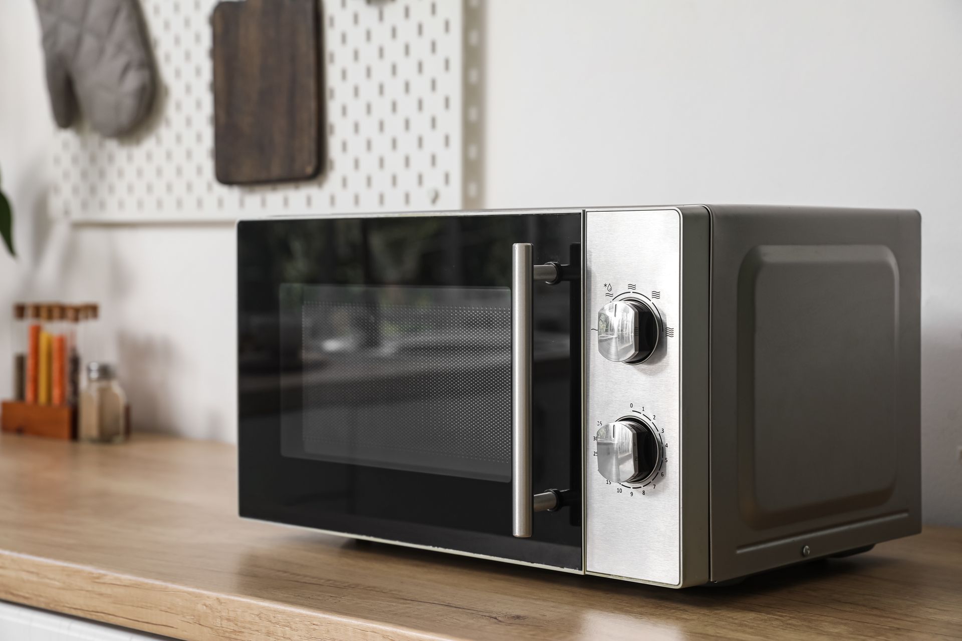 Black and silver microwave on a kitchen countertop with wood accents