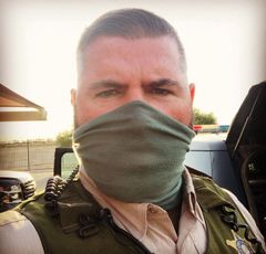 A man wearing a green bandana around his face