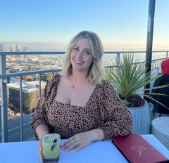 A woman is sitting at a table with a drink in her hand.