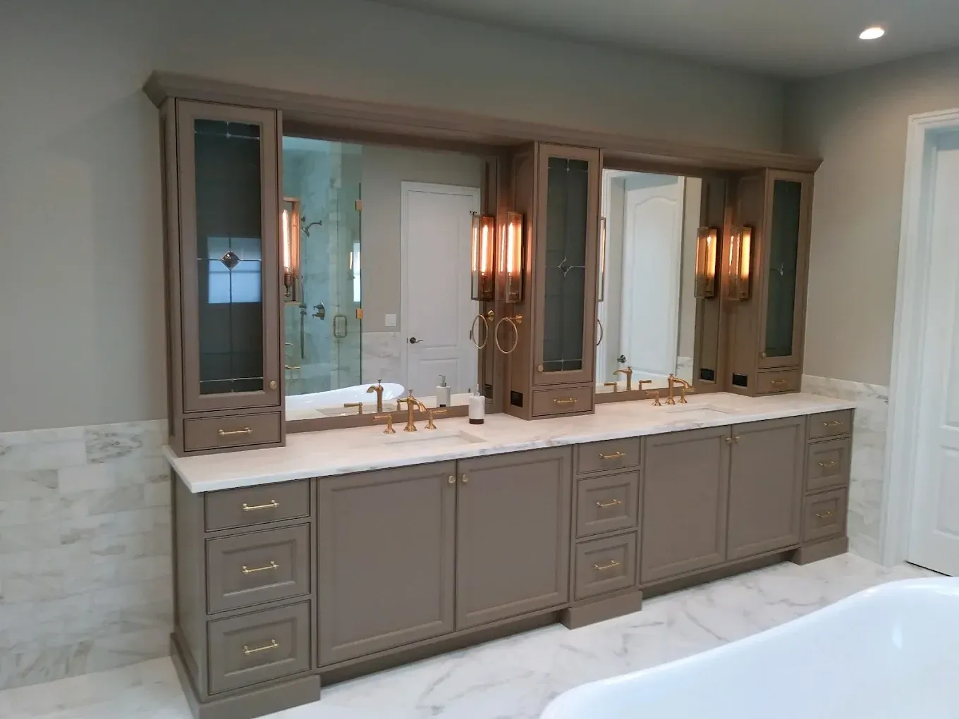 Modern bathroom with double vanity, large mirrors, and marble tile accents