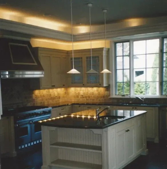 Modern kitchen with dark range, island, pendant lights, and a large window.