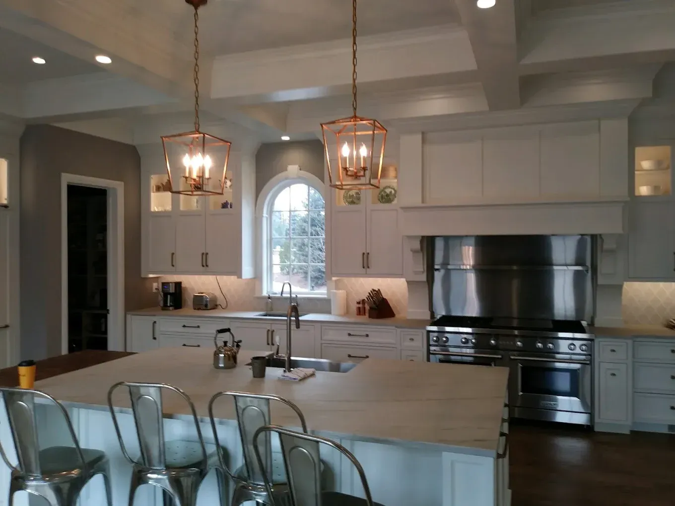 Modern kitchen with island, pendant lights, bar stools, and stainless steel appliances