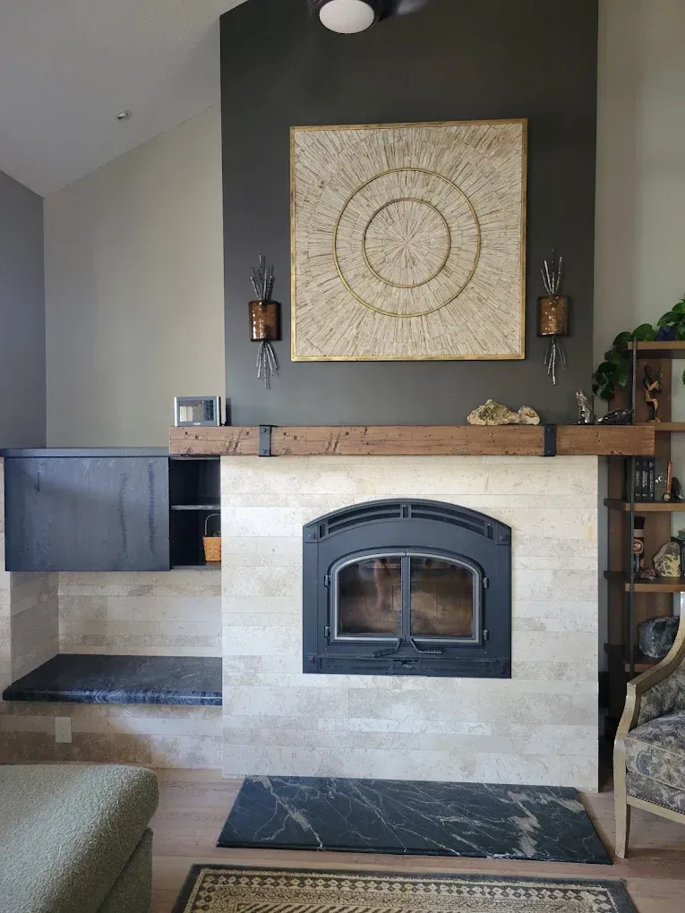 Living room fireplace with light stone surround, dark wood mantel, and decorative wall art above.