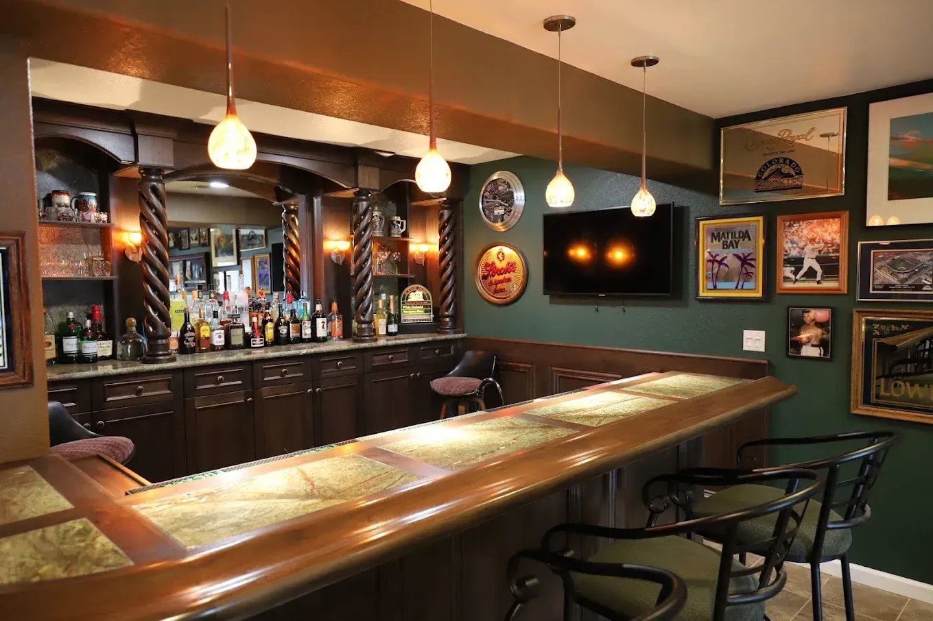 Cozy empty bar with wooden counter, hanging lights, backlit shelves, and framed wall art