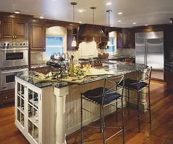 Modern kitchen with large island, stainless steel appliances, wood cabinets, and bar stools