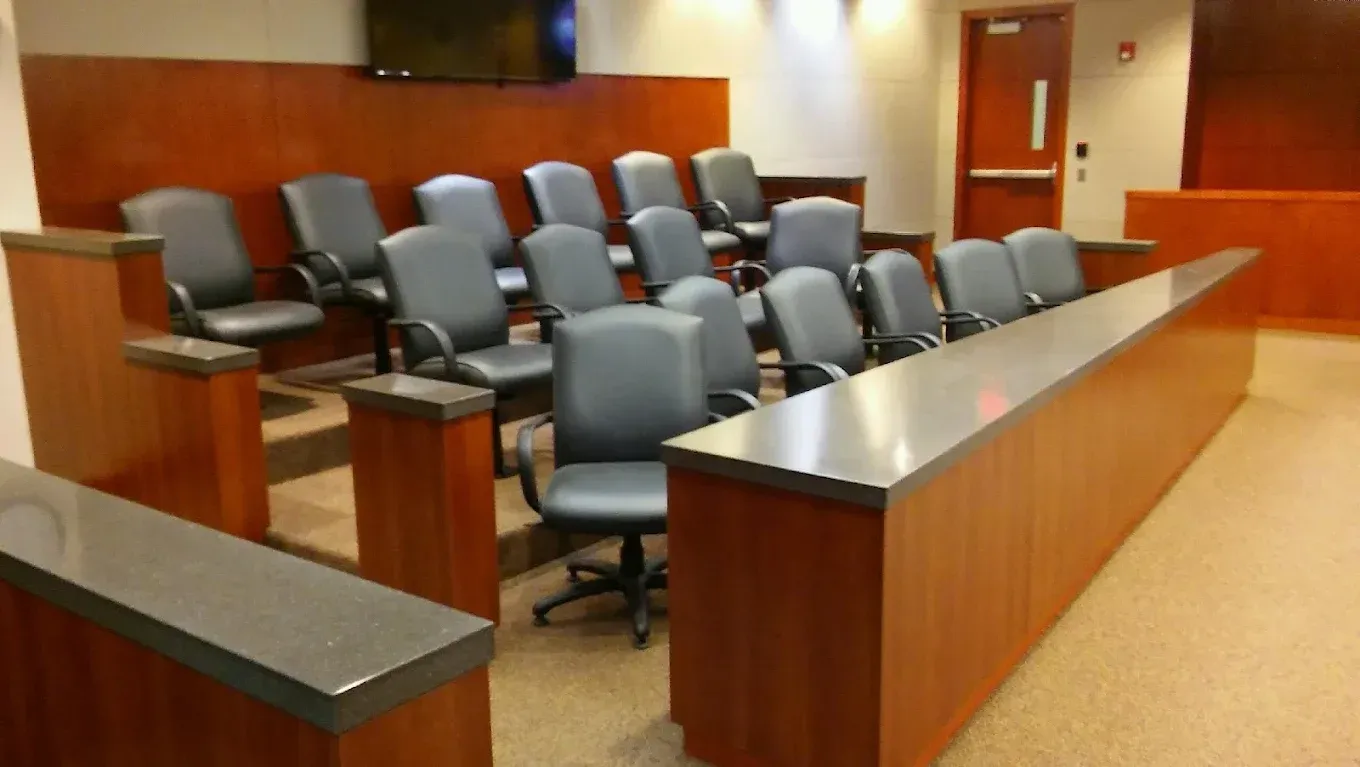 Empty courtroom with gray chairs and wood-paneled benches