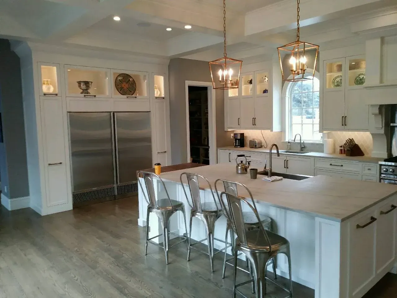 Bright modern kitchen with stainless steel appliances, white island, pendant lights, and barstools.