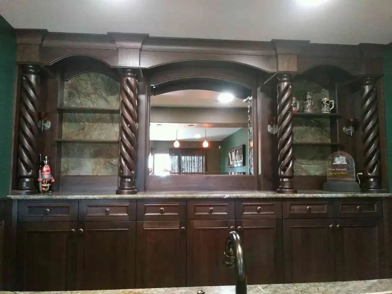 Dark wood built-in bar cabinet with shelves, mirror, and countertops in a room