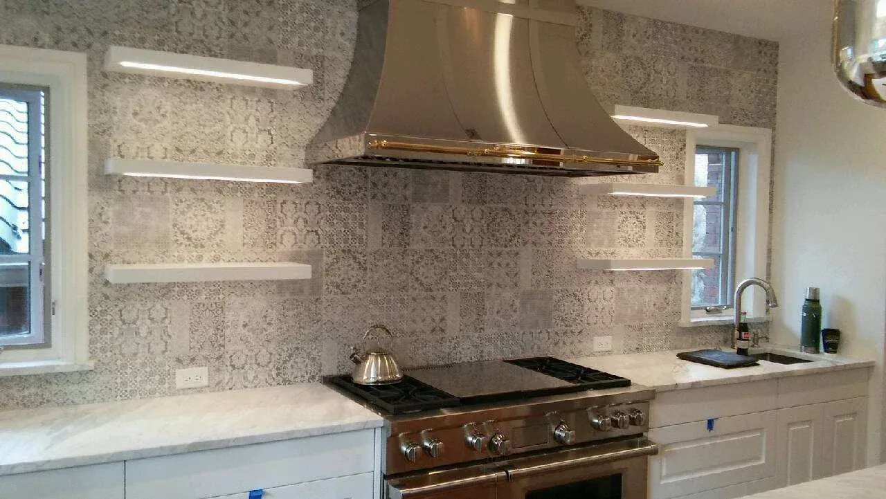 Modern kitchen with stainless range hood, patterned backsplash, open shelves, and white cabinets