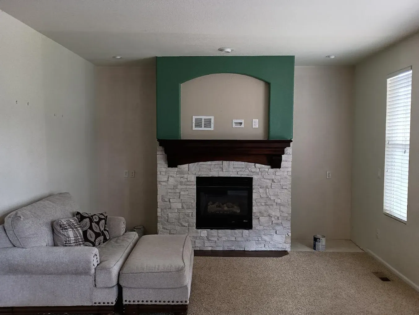 Living room with gray sectional, white brick fireplace, and green accent wall