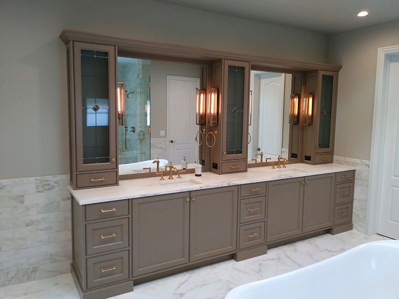 Bathroom vanity with two sinks, mirrors, and built-in cabinets in a neutral color.