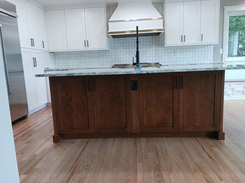 Kitchen with white cabinets, brown island, granite countertops, and hardwood floors.