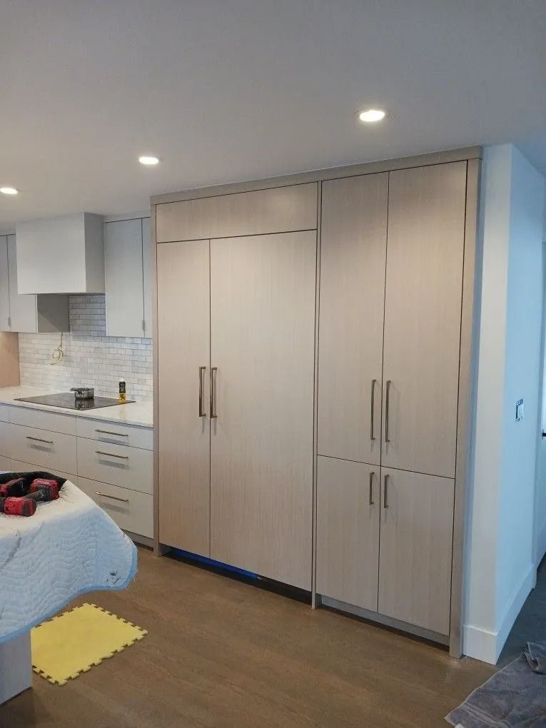 Kitchen with tall, light-colored cabinets. Refrigerator on the left, other storage on the right. Modern design.