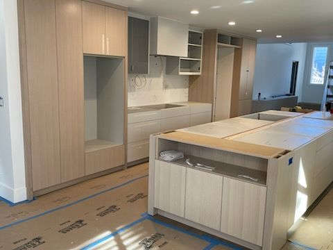 Modern kitchen with light wood cabinets, island, and unfinished floor installation