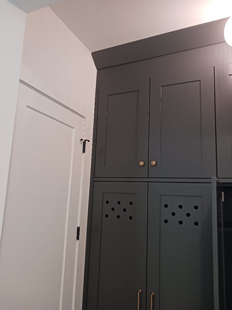 Dark gray built-in cabinet beside a white door in a room corner
