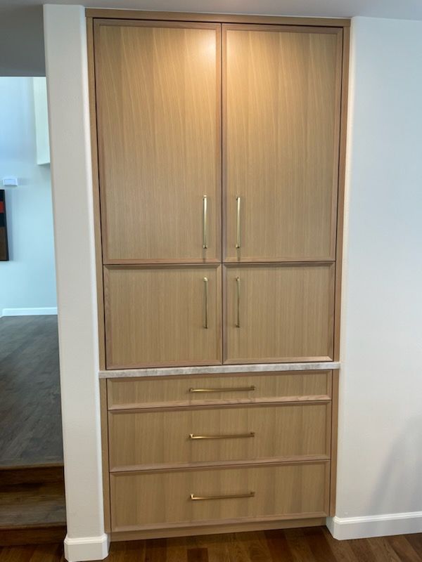 Built-in wood cabinet with double doors and drawers in a hallway niche