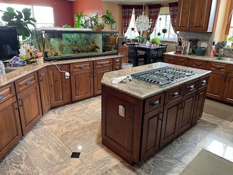 Spacious kitchen with wood cabinets, central island cooktop, and large aquarium by the window