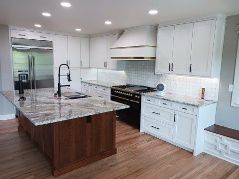 Modern white kitchen with marble island, stainless steel appliances, and light wood floors