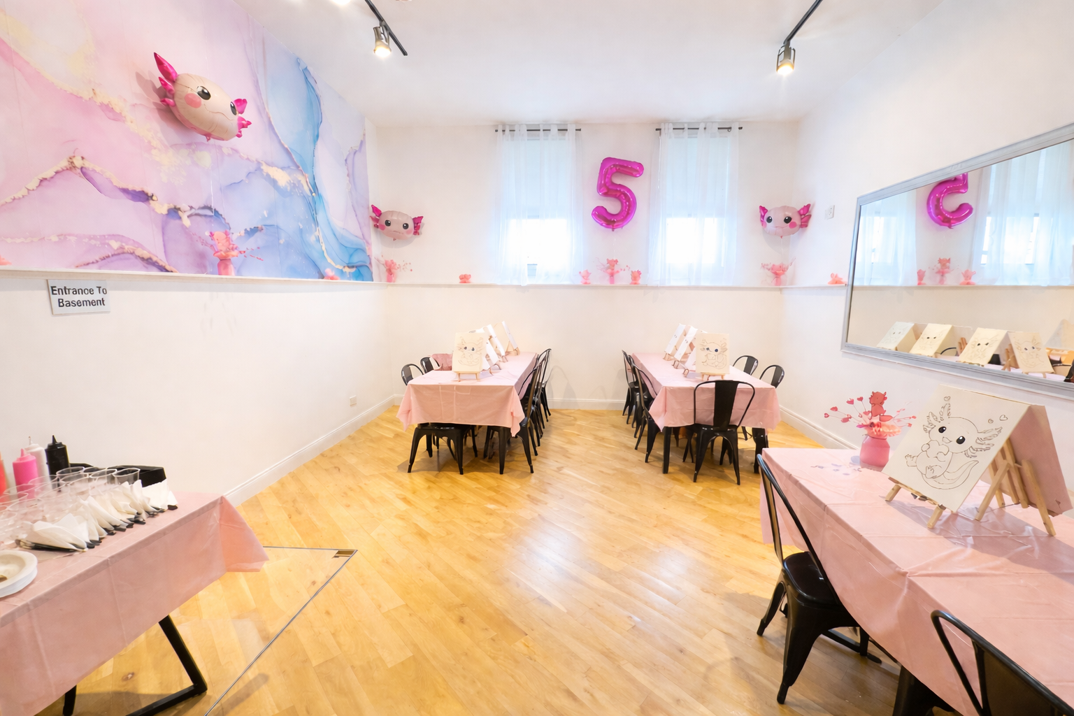 Bright pink-themed party room with tables, chairs, and large number decorations on the walls