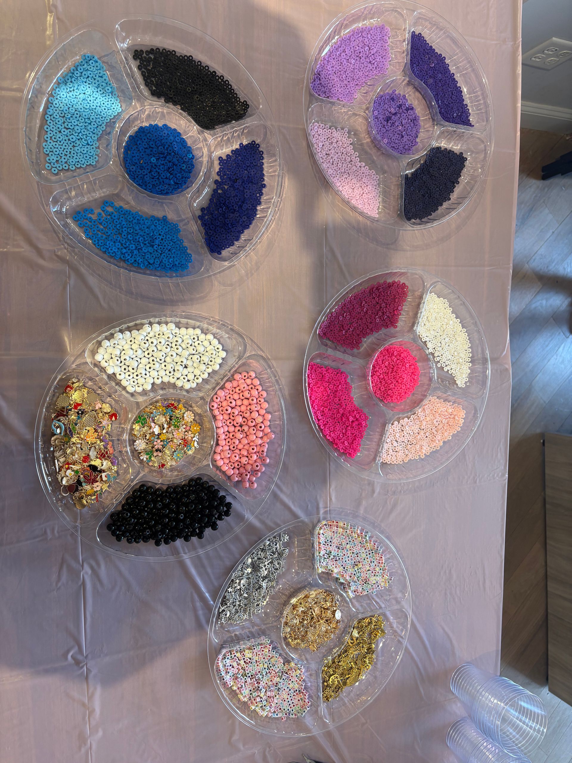 Five glittery circular art pieces in blue, purple, pink, gold, and silver arranged on a translucent surface
