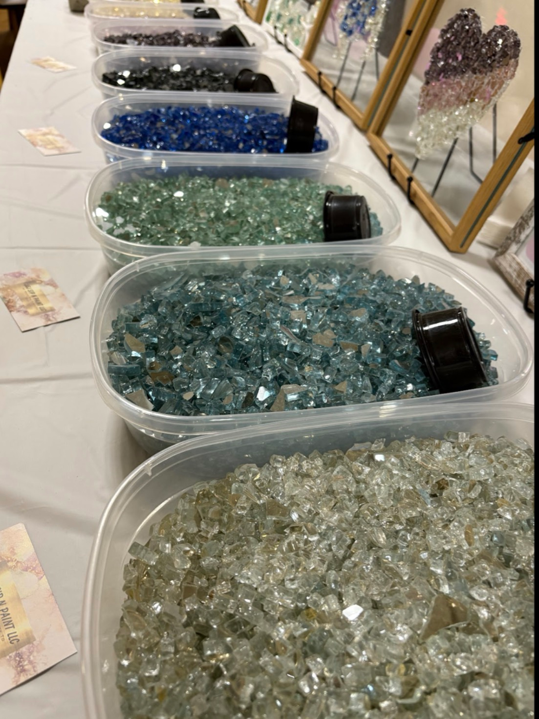 Trays of assorted colorful gemstones and crystals displayed on a table