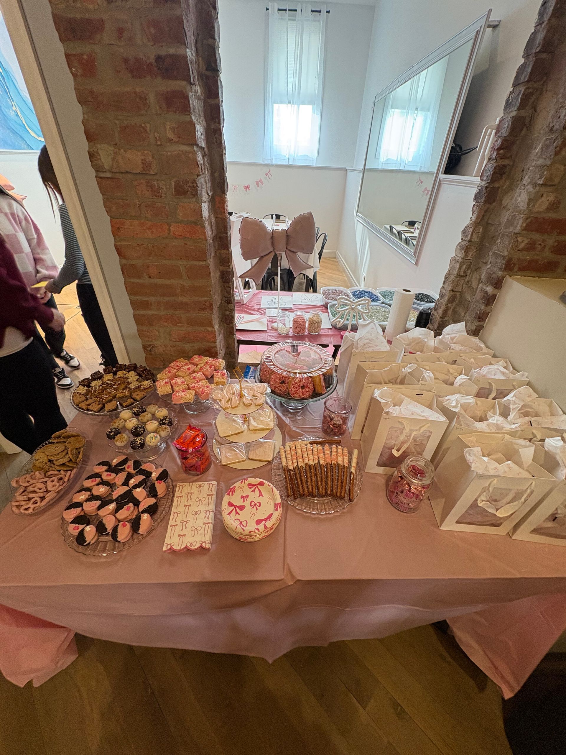 Table of assorted desserts and gift bags at a party setup in a bright room