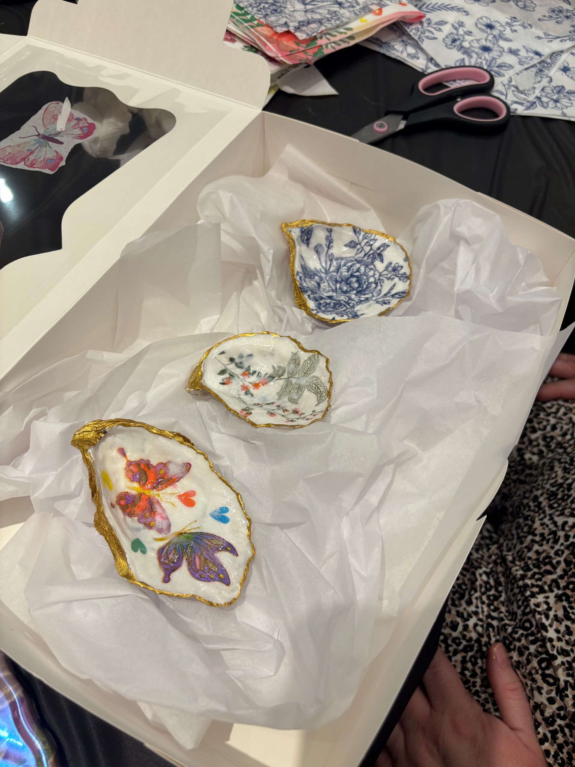 Three decorated egg-shaped ornaments in tissue paper on a table, with scissors nearby.