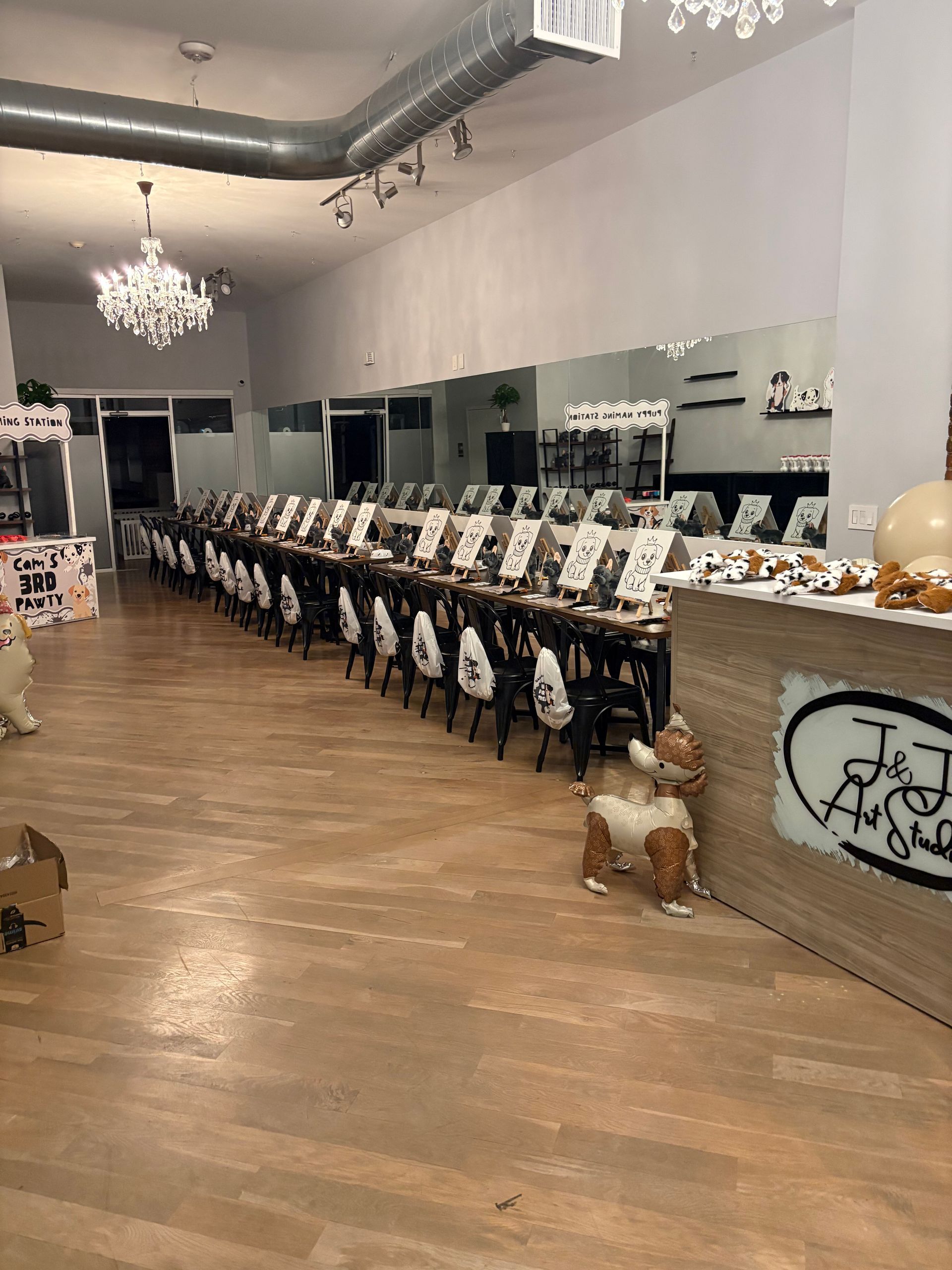 Long banquet table set with white tableware in a bright hall with chandeliers and wooden floors