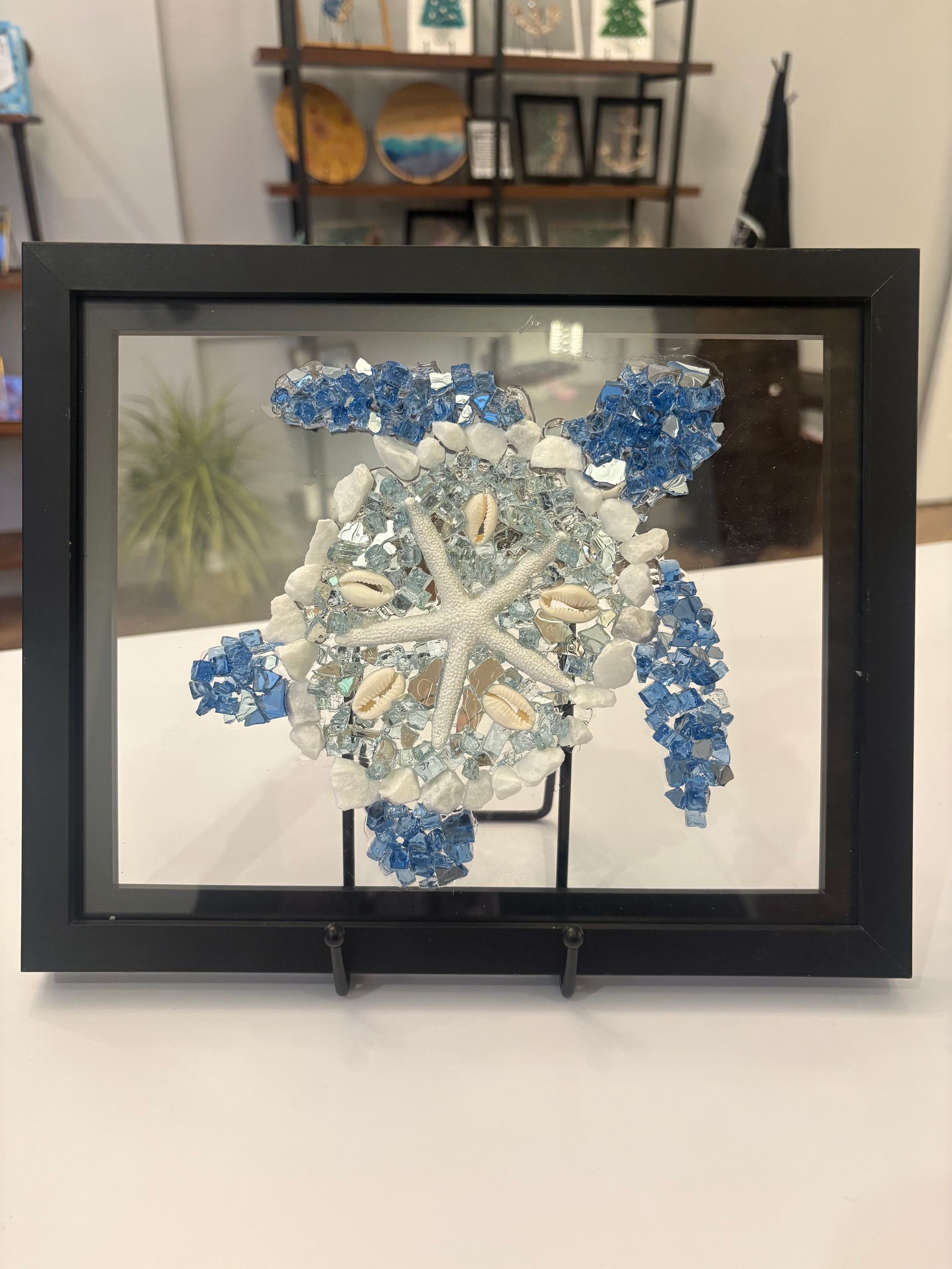 Blue and white snowflake artwork in a black frame on a wall