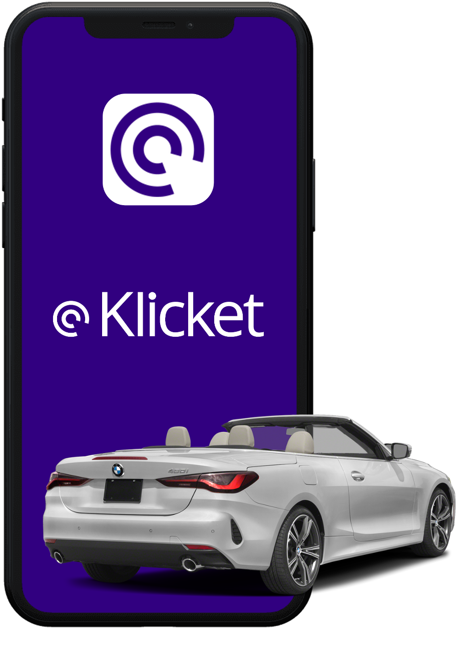 Smartphone with @Klicket logo overlaid on a purple screen, with a silver convertible car in front.