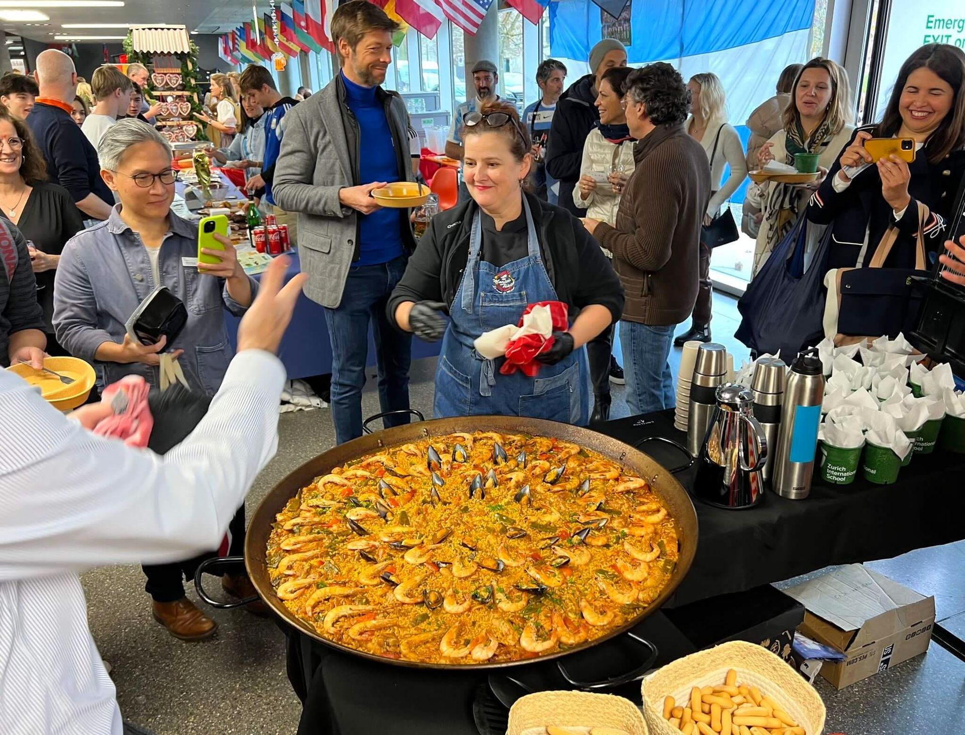 Un grupo de personas está de pie alrededor de una gran sartén con comida en Suiza