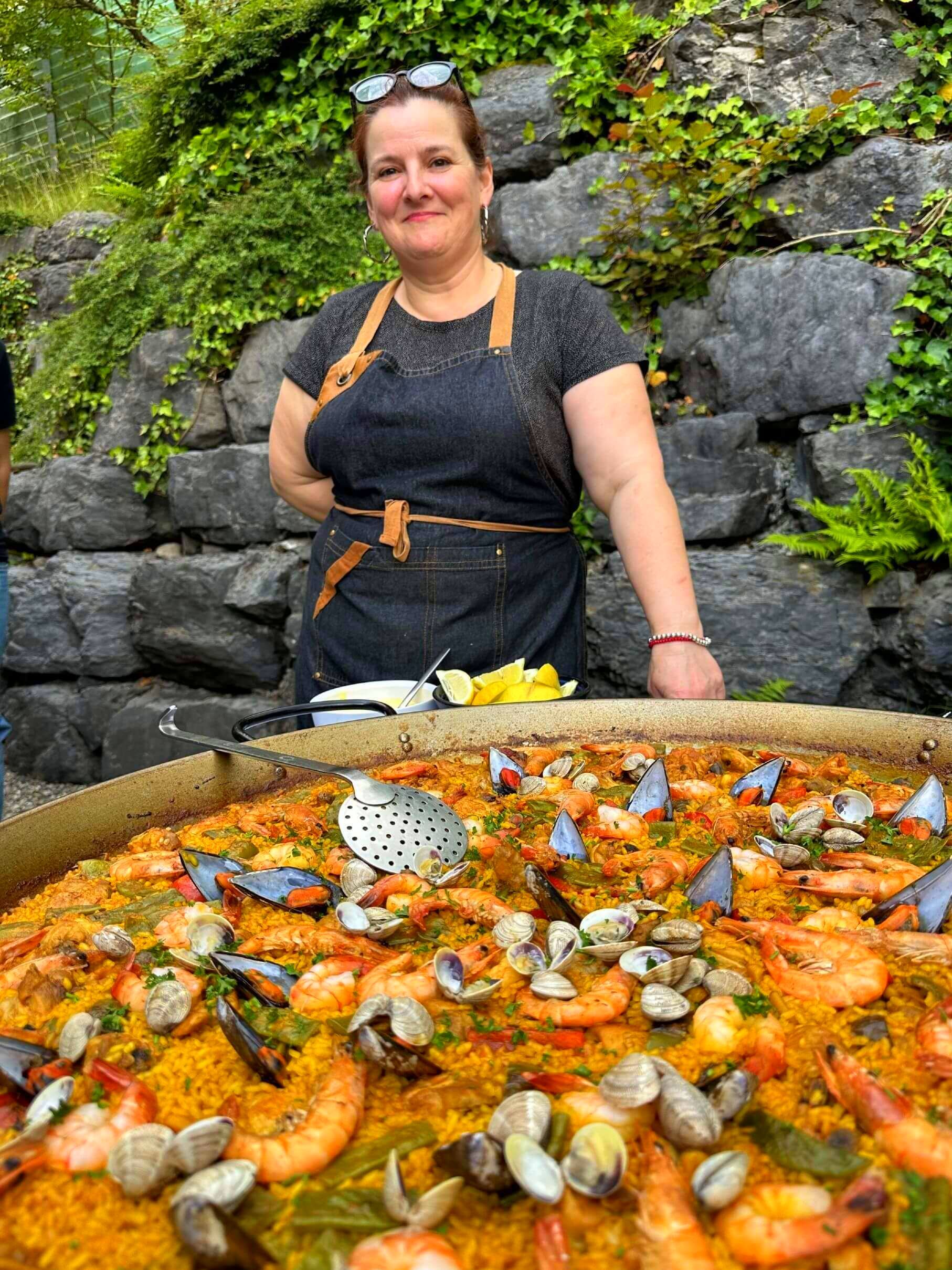 Mariví está parada frente a una gran sartén con paella en un evento en Suiza