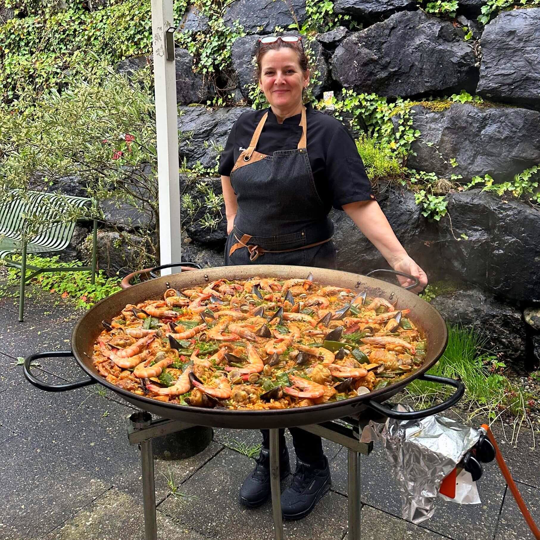 Mariví está parada frente a una gran olla de comida en Suiza