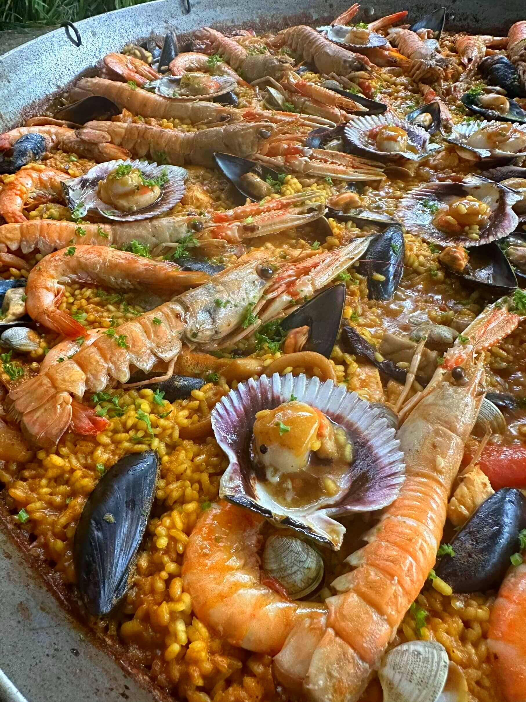 Una sartén grande llena de arroz, camarones, mejillones y vieiras.