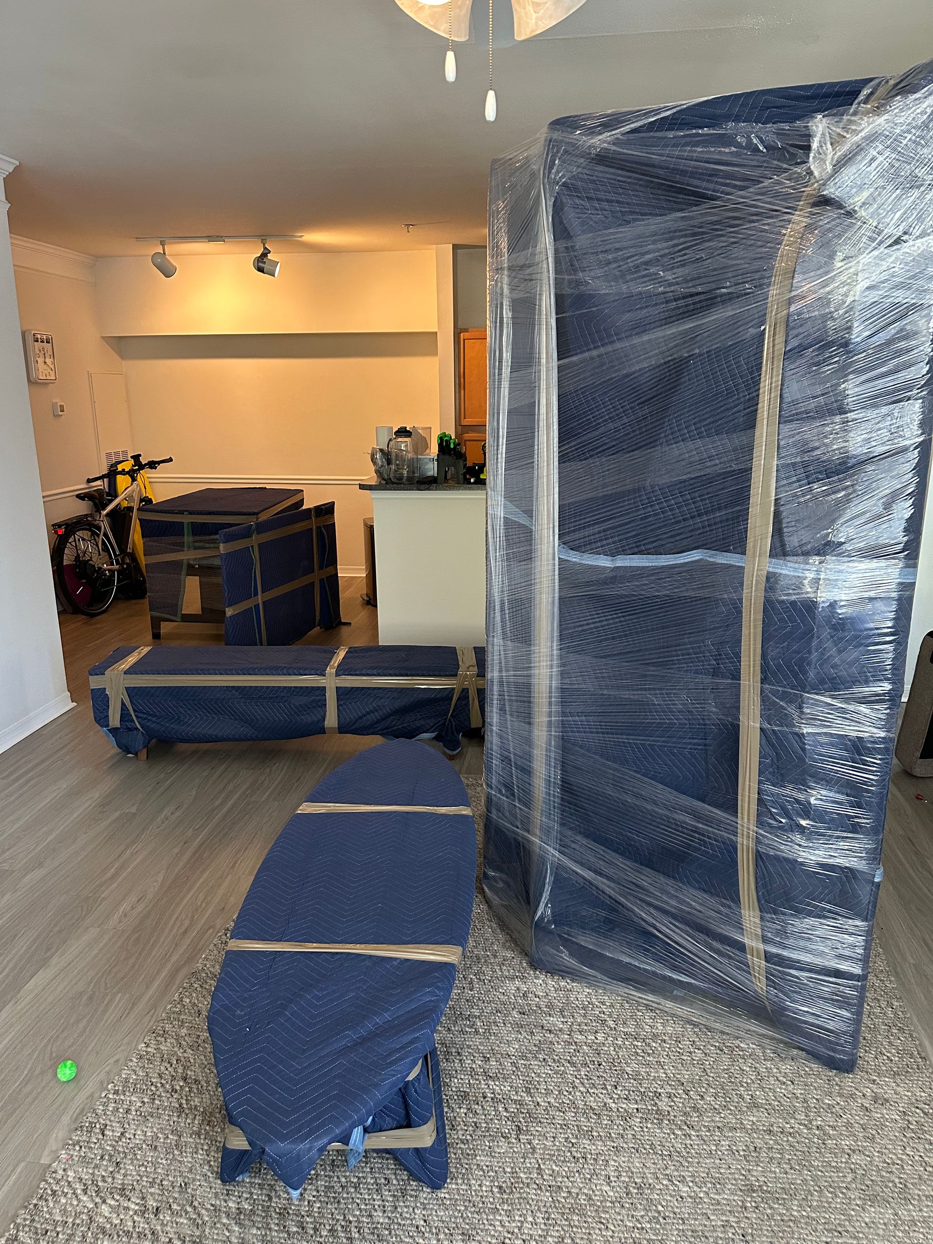 A living room filled with furniture wrapped in plastic wrap.