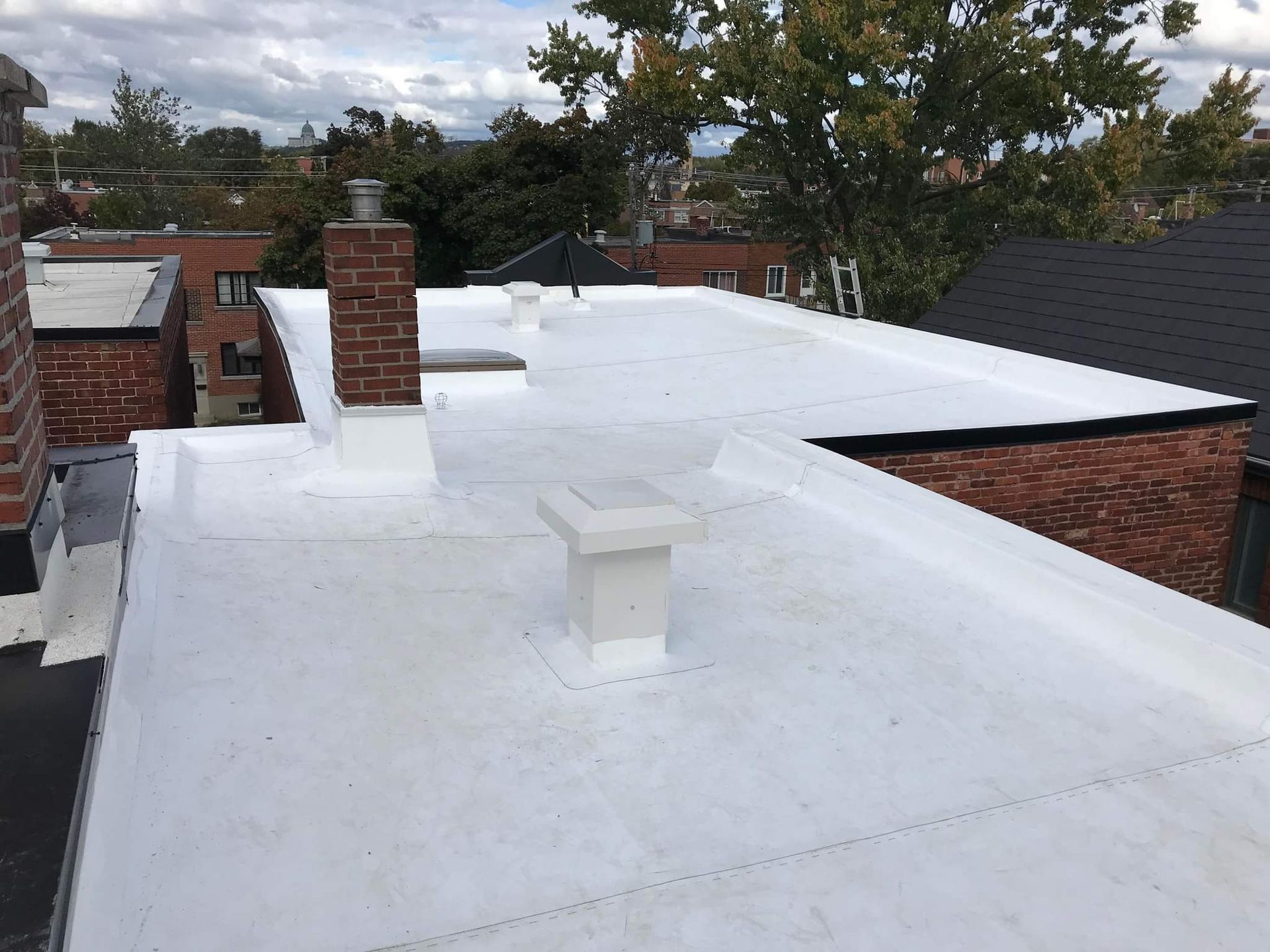 Un toit blanc avec des cheminées dessus repose sur un bâtiment en briques.